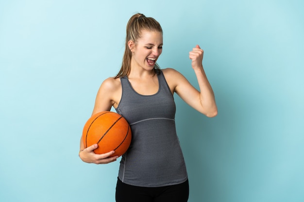 Молодая женщина играет в баскетбол, изолированные на синем фоне, празднует победу