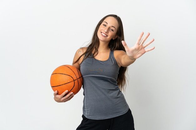 Young woman playing basketball over isolated white background counting five with fingers