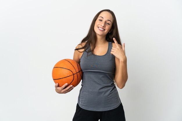 Young woman playing basketball over isolated white background giving a thumbs up gesture