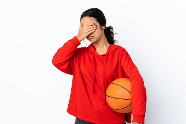 Giovane donna che gioca a basket su sfondo bianco isolato che fa il gesto di arresto e che copre il viso