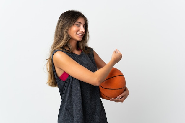 Молодая женщина играет в баскетбол, изолированные на белом фоне, указывая назад