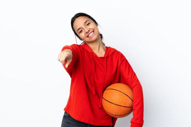 Young woman playing basketball over isolated white background pointing front with happy expression