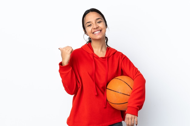 Young woman playing basketball over isolated white background with thumbs up gesture and smiling