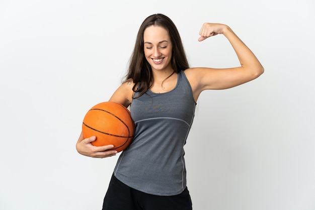 Young woman playing basketball over isolated white wall doing strong gesture