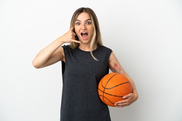 Young woman playing basketball over isolated white wall making phone gesture. Call me back sign