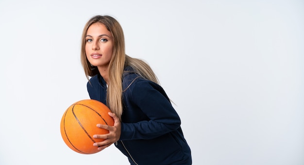 Young woman playing basketball over isolated white 