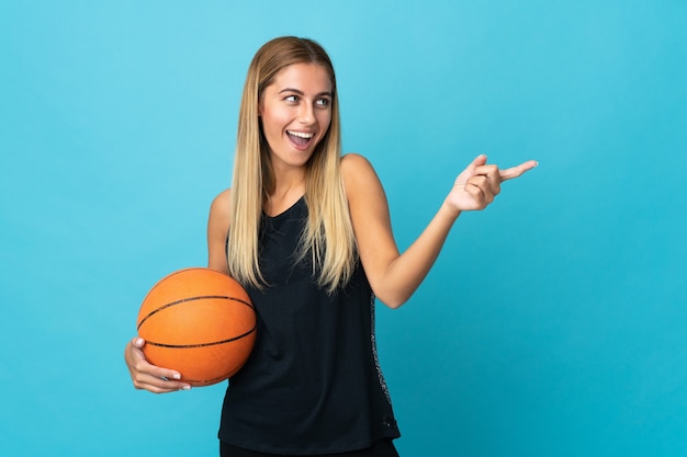 빈 벽에 고립 된 농구 포즈를 취하는 젊은 여자