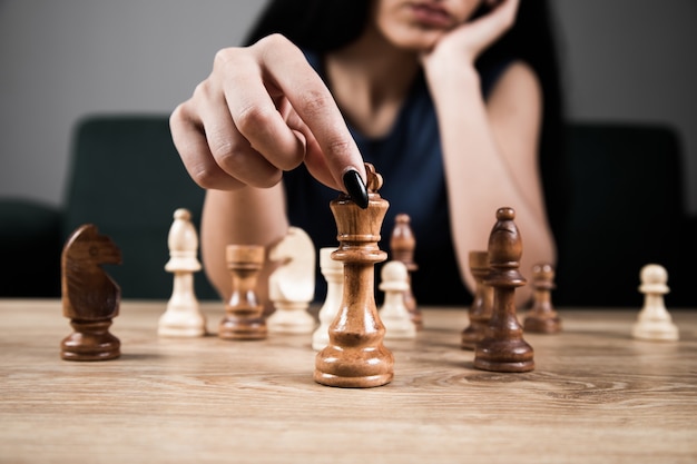 Young woman playing chess alone