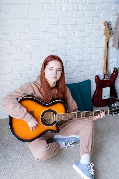 Young woman playing guitar at home