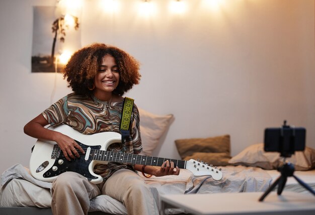 Молодая женщина играет на гитаре дома