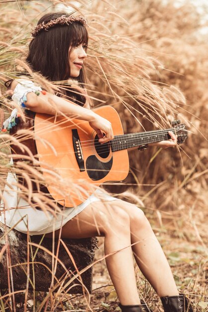 写真 フィールドでギターを弾く若い女性