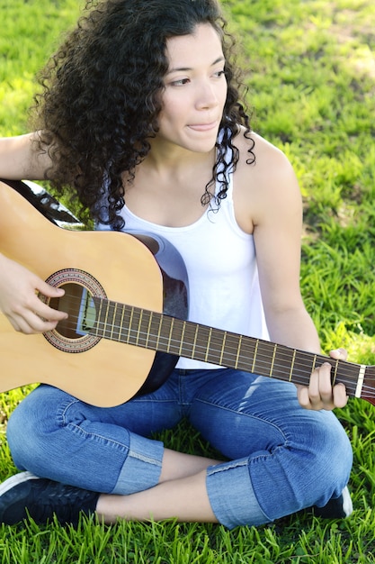 公園でギターを演奏する若い女性。