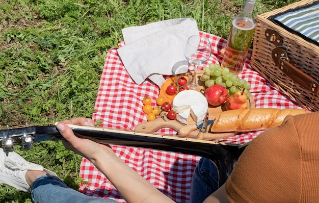 Foto giovane donna che suona la chitarra su un picnic vista da dietro