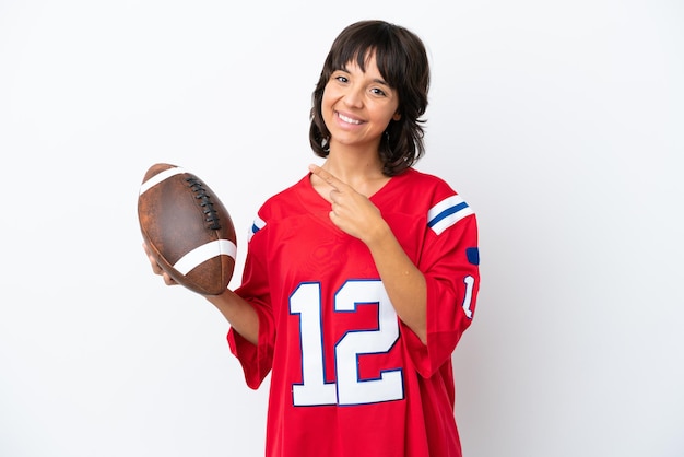 Young woman playing rugby isolated on white background pointing\
to the side to present a product