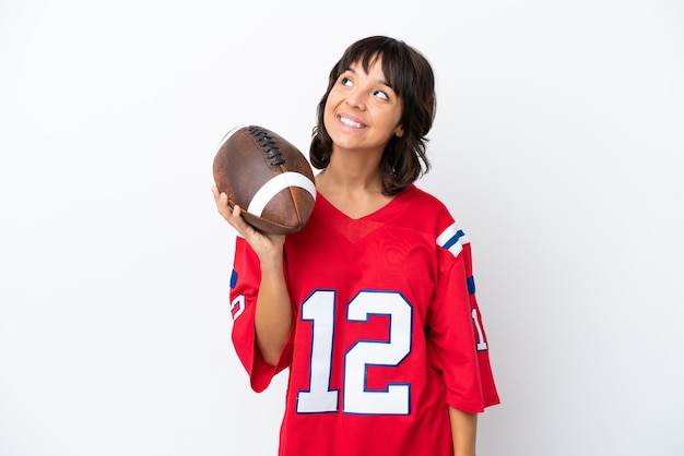 Young woman playing rugby isolated on white background thinking an idea while looking up