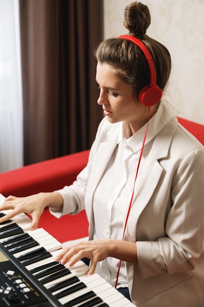 Young woman playing synthesizer at home