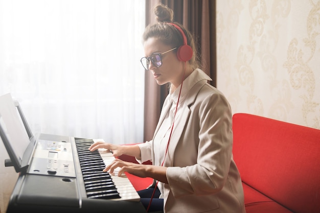 Young  woman playing synthesizer at home