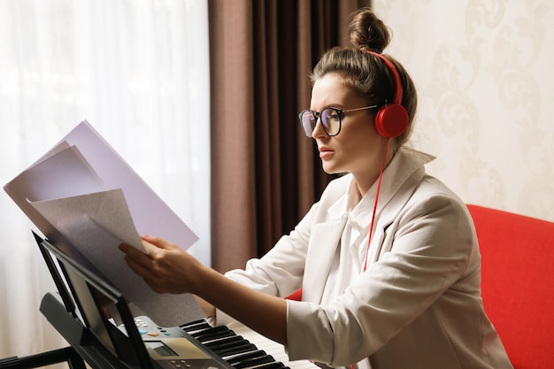 Молодая женщина играет на синтезаторе дома