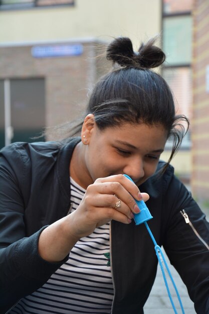 Photo young woman playing with bubble wand in city