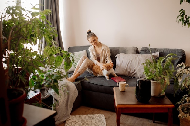 Young woman playing with cat at home