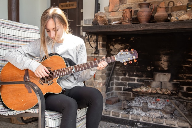 A young woman plays the guitar in a cozy atmosphere. The concept of Hobbies and recreation.