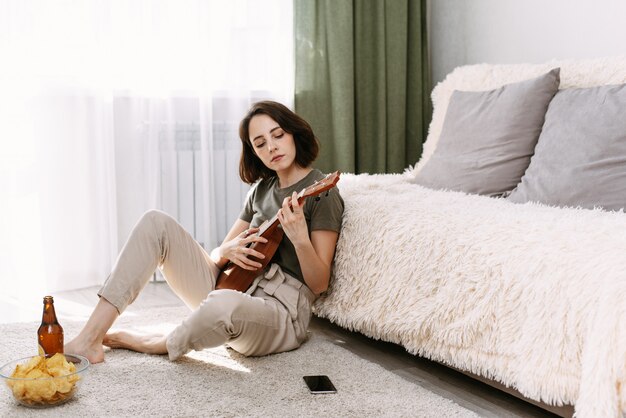 A young woman plays ukulele