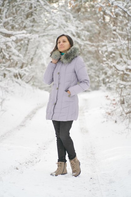 Young woman plays with a snow in sunny winter day