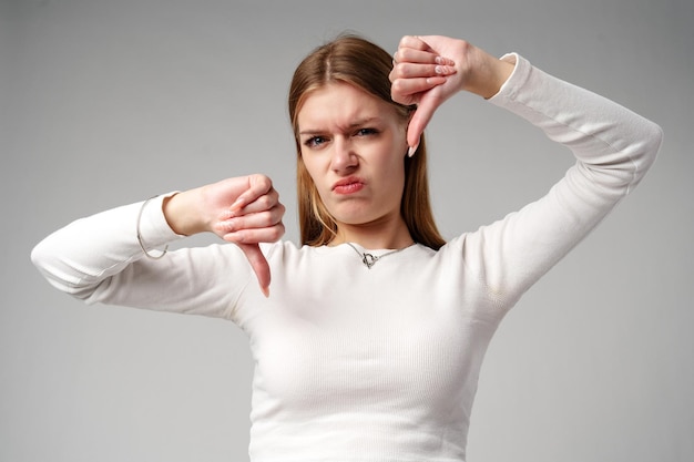 Young woman pointing finger down at camera in studio