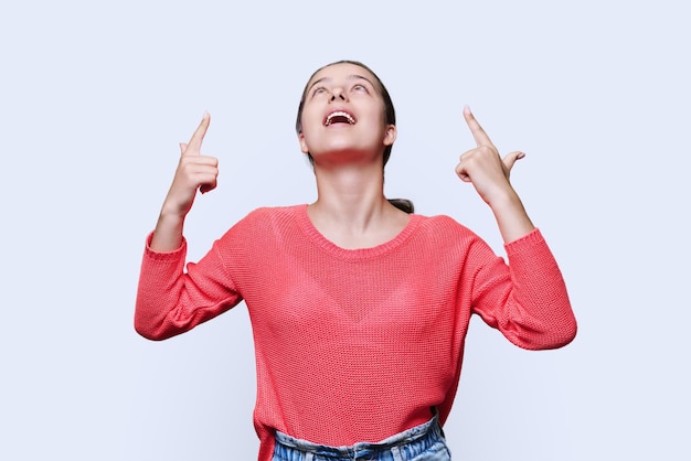 Young woman pointing fingers up space for copyspace text on white background