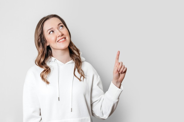 Young woman pointing her finger up at copy space isolated on white background