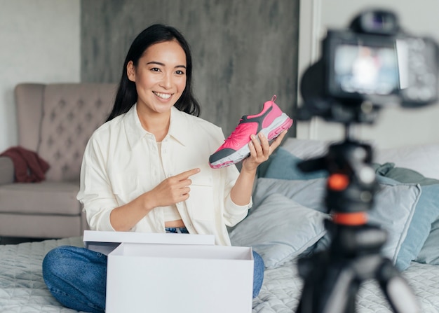 Young woman pointing to a sneaker while vlogging