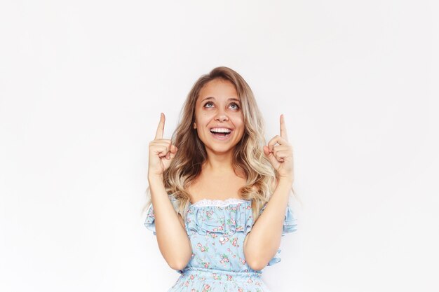 A young woman points up to a empty copy space for text or design with two fingers presenting product