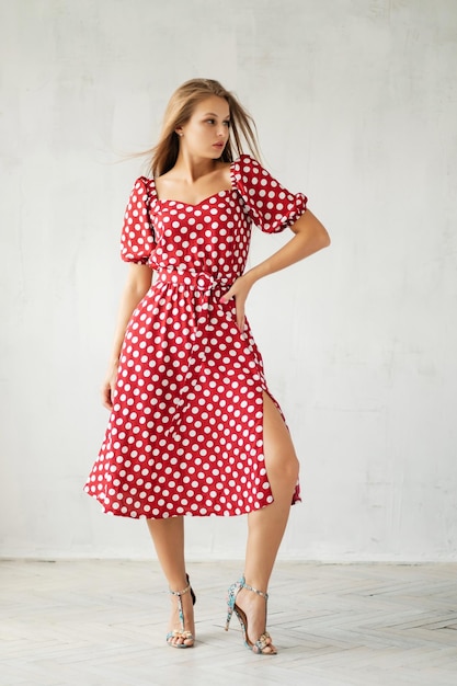 Young woman in polkadot dress at grey wall Summer women's wardrobe