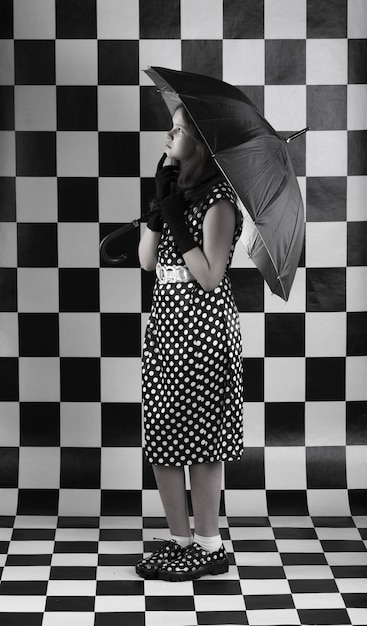 Photo young woman in polkadot dress and with a black umbrella