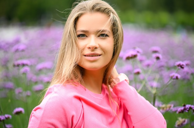 Young woman portrait posing against purple flowers