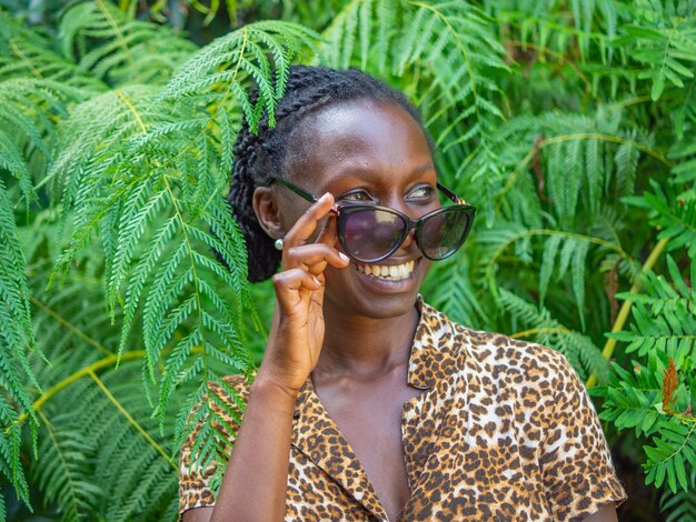 Foto ritratto di una giovane donna sorridente che indossa occhiali da sole su uno sfondo verde