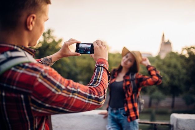 Young woman poses on excursion in tourist town. Summer hiking of love couple. Hike adventure of young man and woman