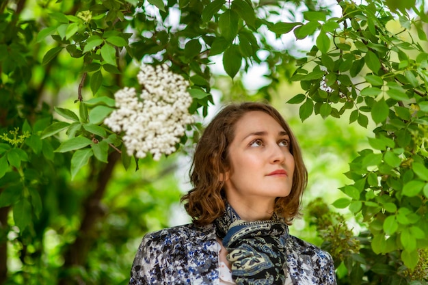 Young woman poses among the plants looking at one of them