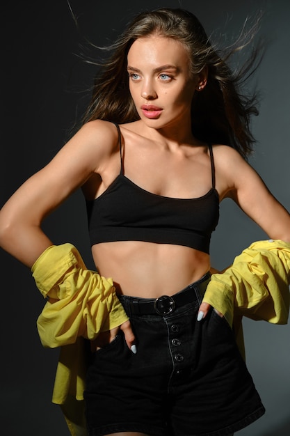 Young woman posing akimbo on dark grey background