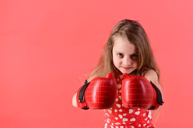 Giovane donna in posa in guantoni da boxe su sfondo rosso