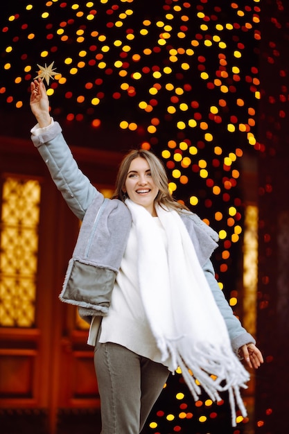 Young woman posing by the christmas tree at winter holidays with christmas star