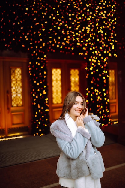 Young woman posing by the christmas tree at winter holidays with christmas star