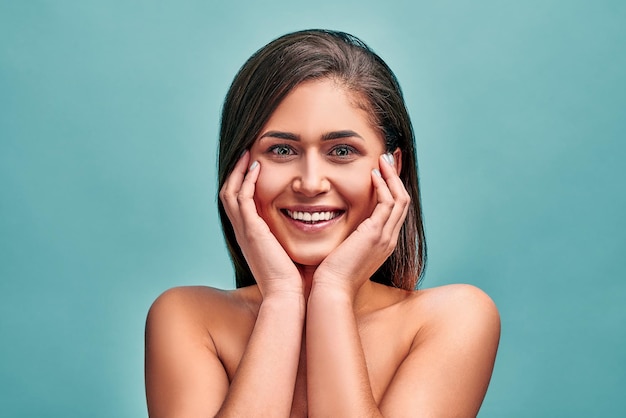 young woman posing at camera in studio on blue background Concept of skin care freshness and youth