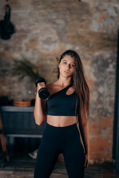 Young woman posing at the camera with dumbbells in her hands