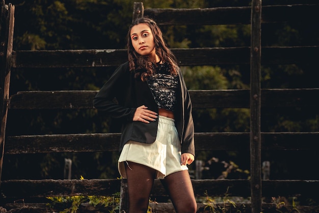 Young woman posing in front of a gate in the countryside