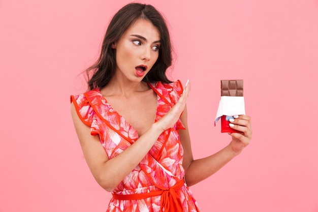 Giovane donna in posa parete isolata che tiene cioccolato che mostra gesto di arresto.