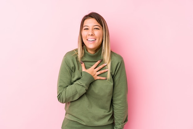 Young woman posing  laughs out loudly keeping hand on chest.