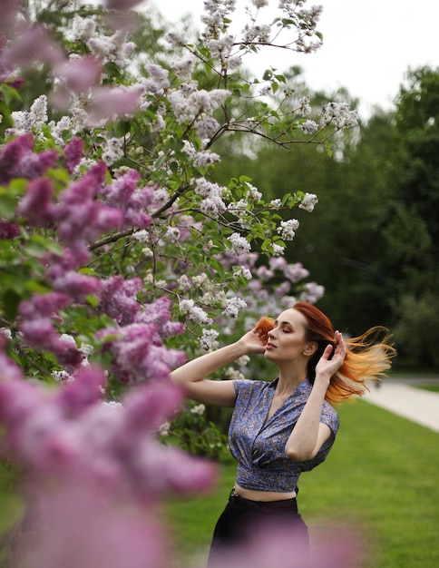 ライラックの花でポーズをとる若い女性