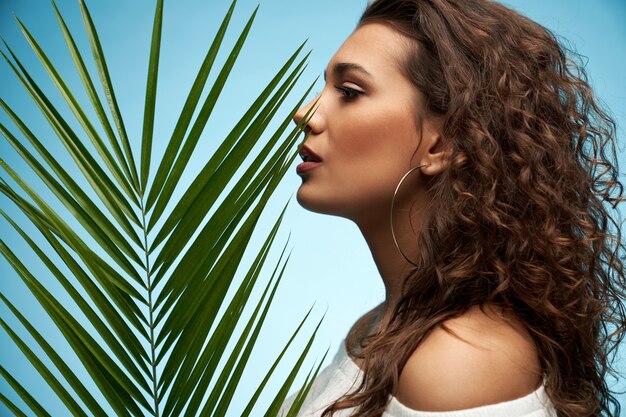 Young woman posing near palm leaf