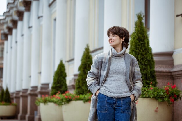 Young woman posing outdoors in a gray coat in spring